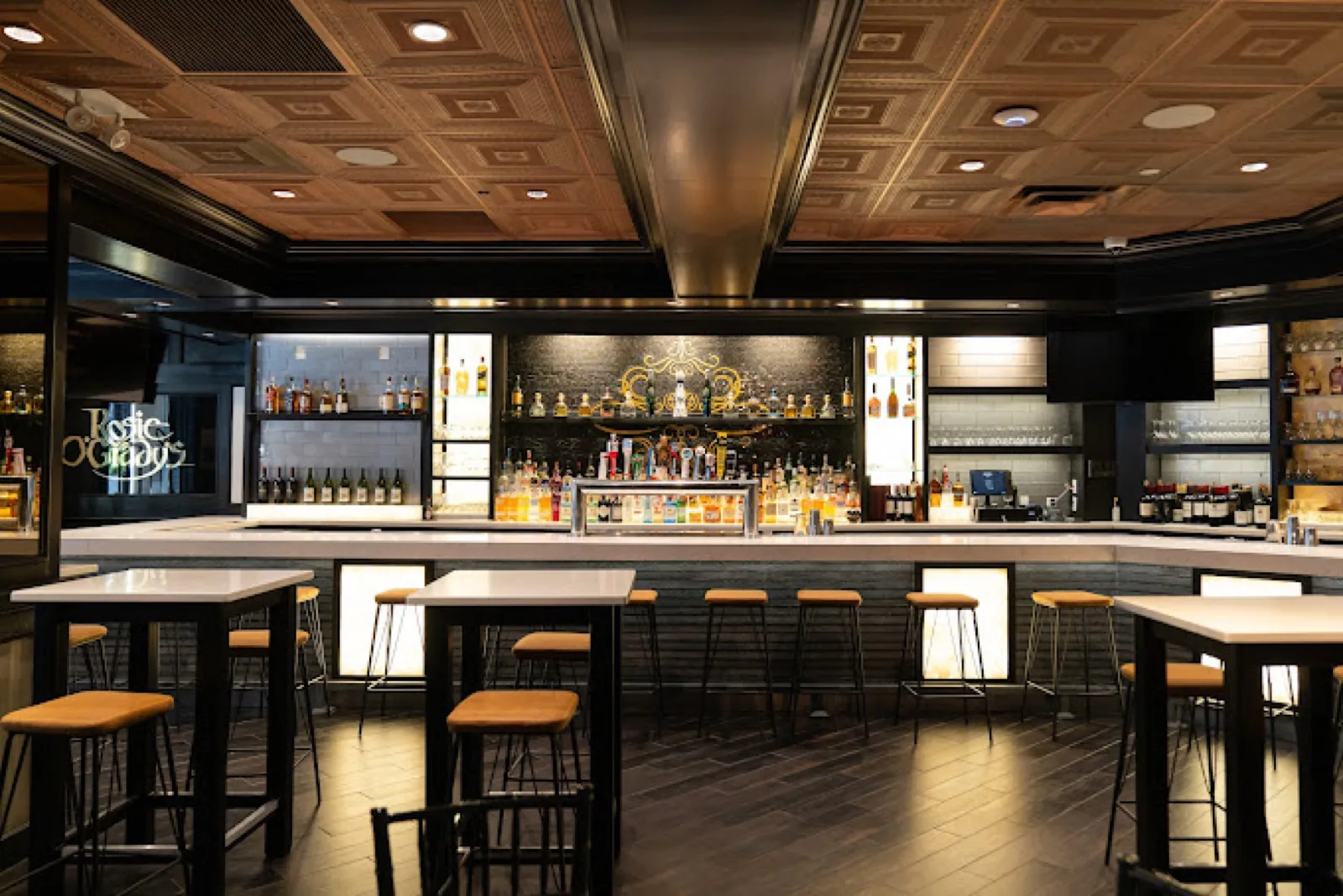 The long white marble bar at Rosie O'Grady's under a coffered brass ceiling, back bar lit, stools waiting