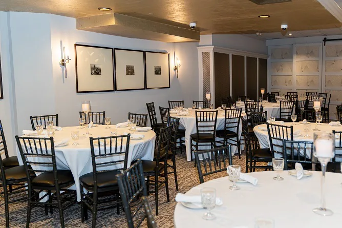 The Broadway Room set for dinner, round tables in white linen under a gold ceiling