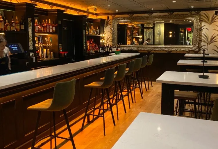 Bar stools along the polished bar in the Side Bar, mirror behind