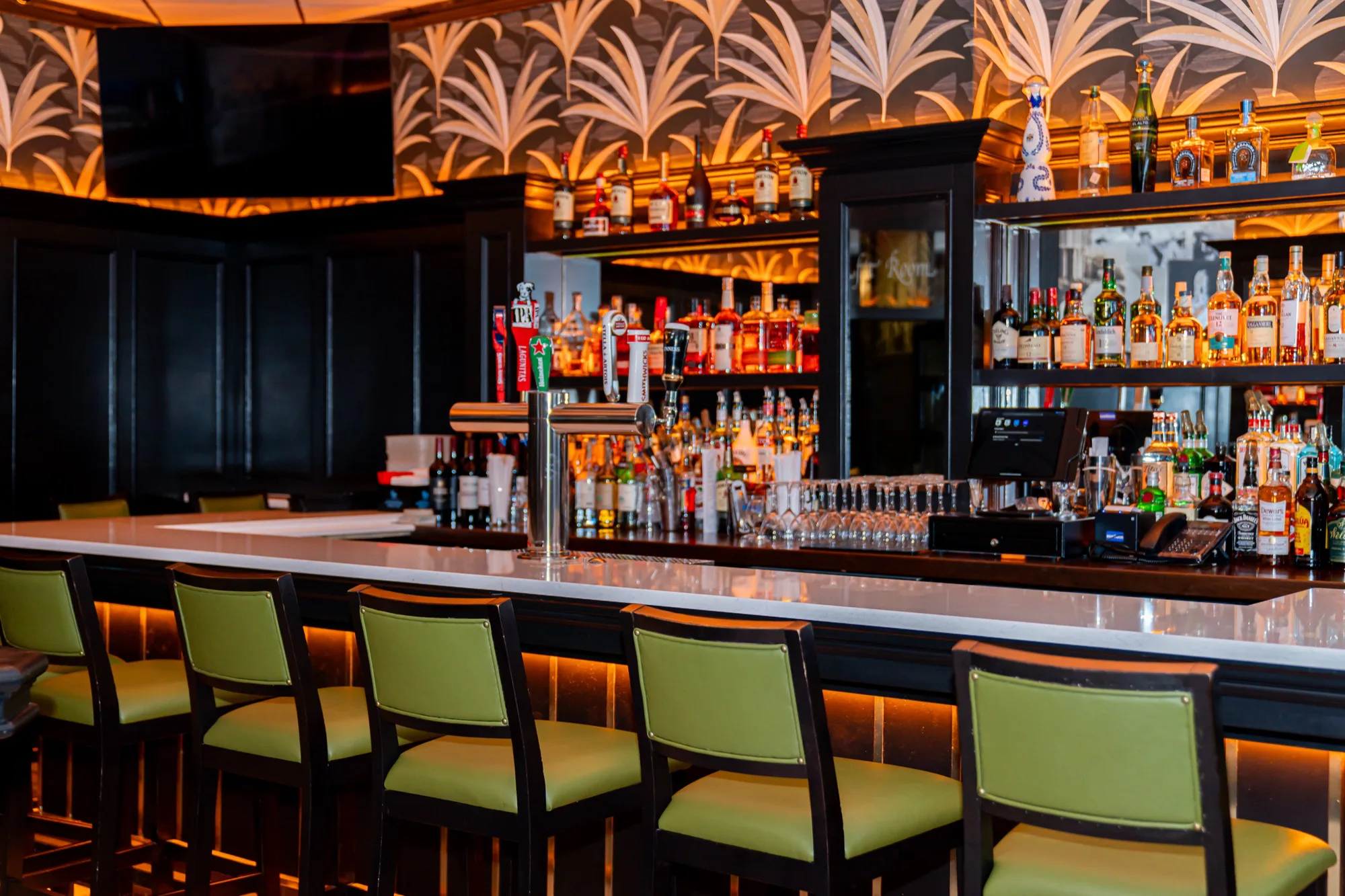 The Taft Bar's back bar under gold palm-leaf wallpaper