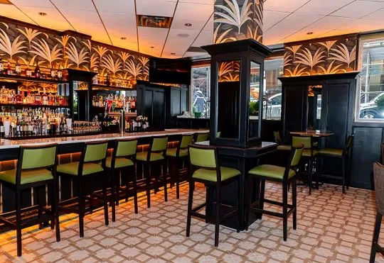 The Taft Bar: dark timber bar, olive leather stools and gold palm-leaf walls