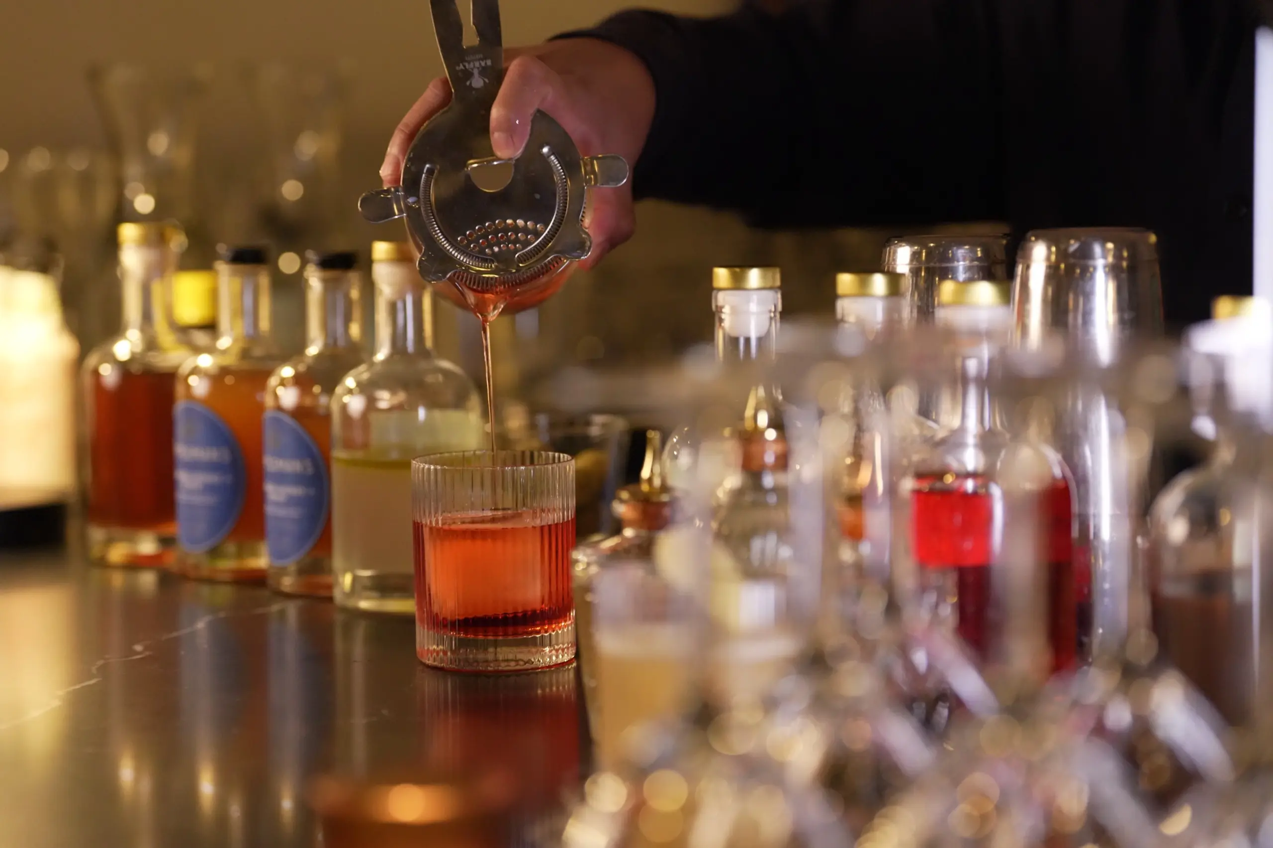 A bartender straining a cocktail at the bar