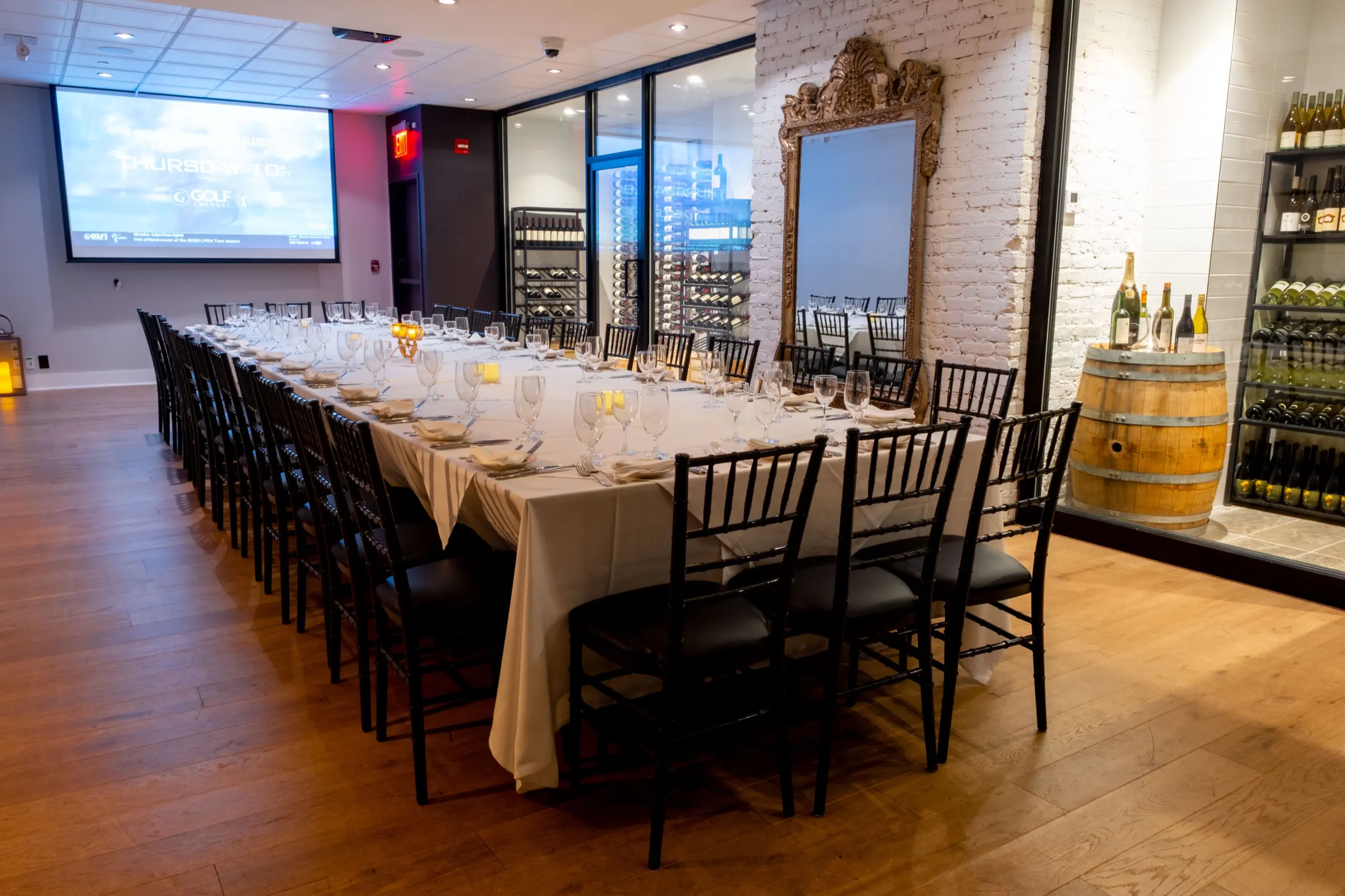 Broadway Room set for a long-table dinner, with the screen and the wine storage