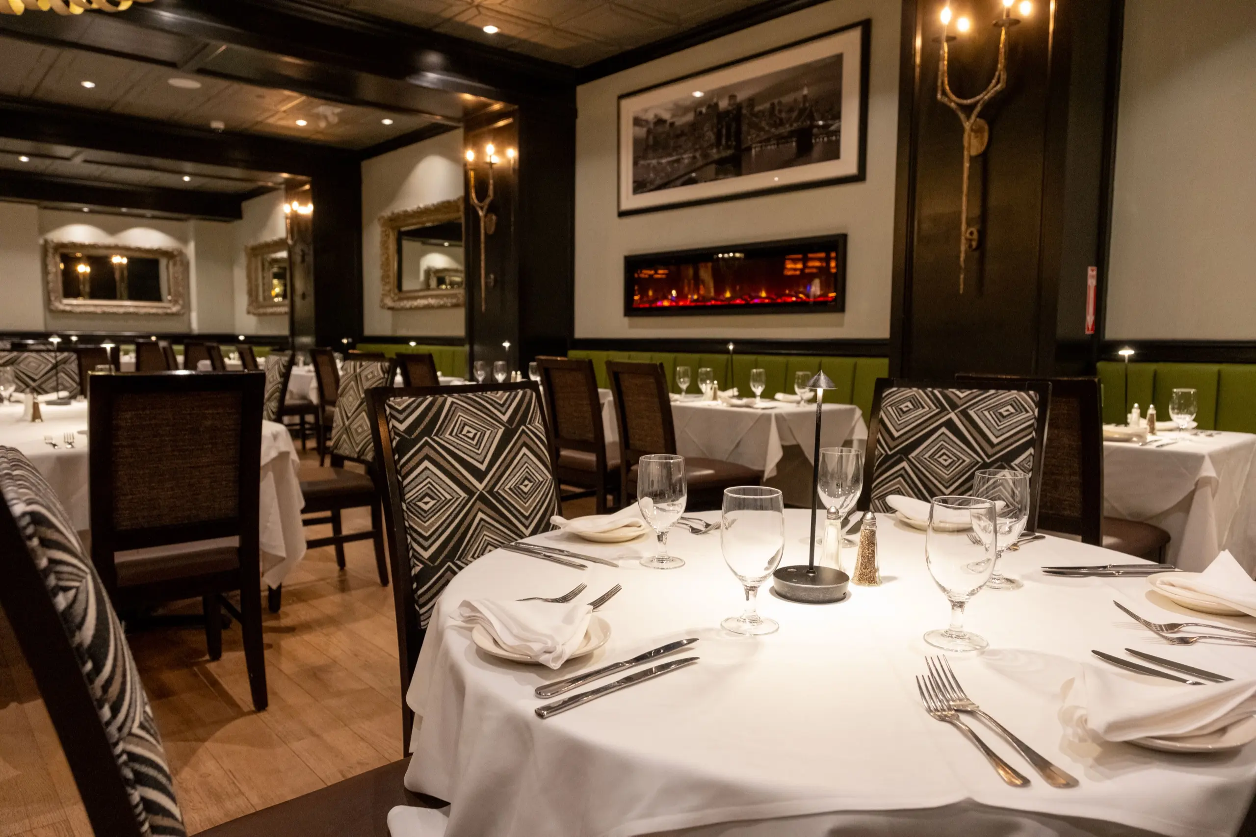 The dining room set for dinner, green banquettes along the wall