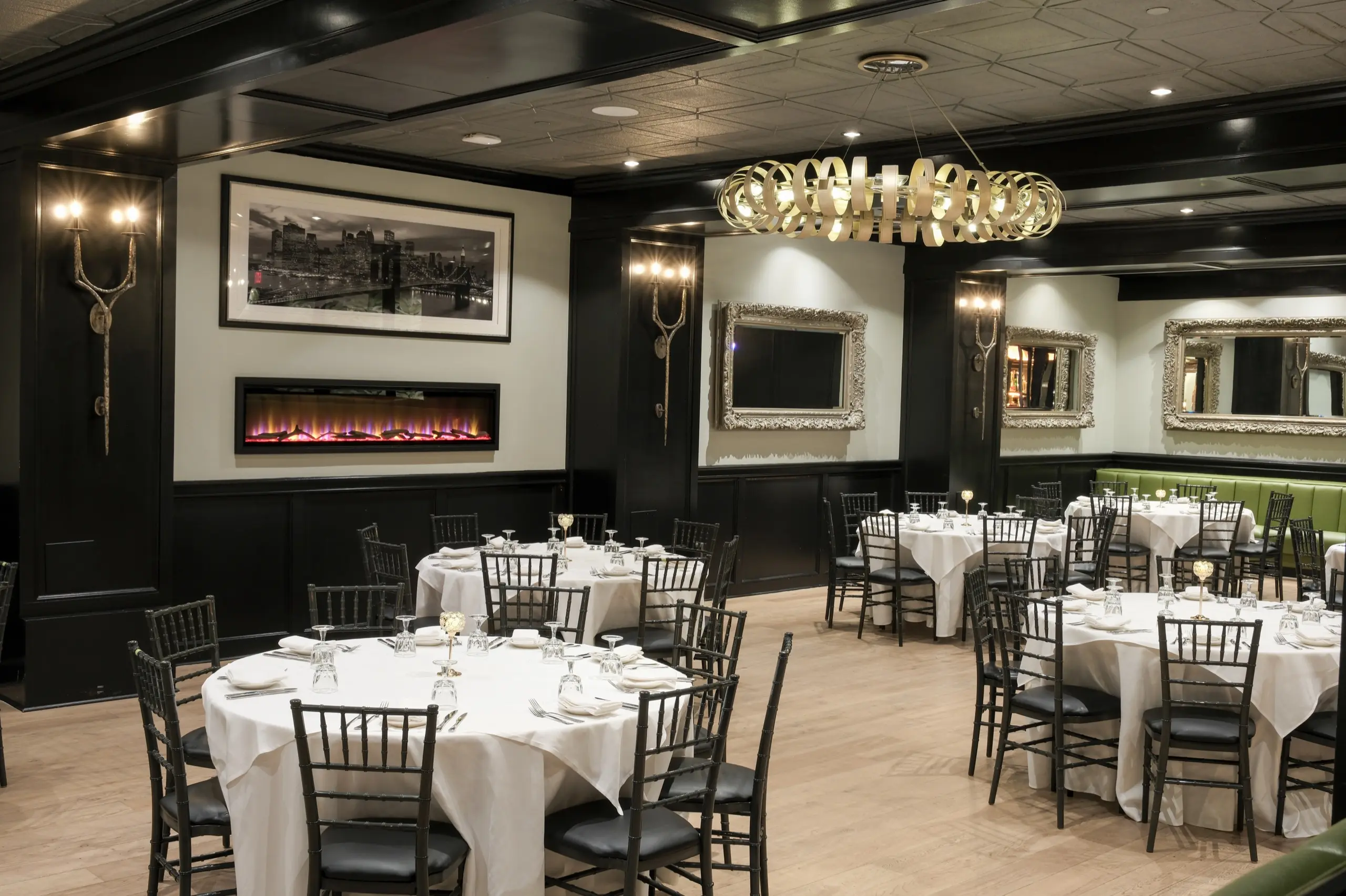 The main dining room with round tables, a fireplace and gilt mirrors