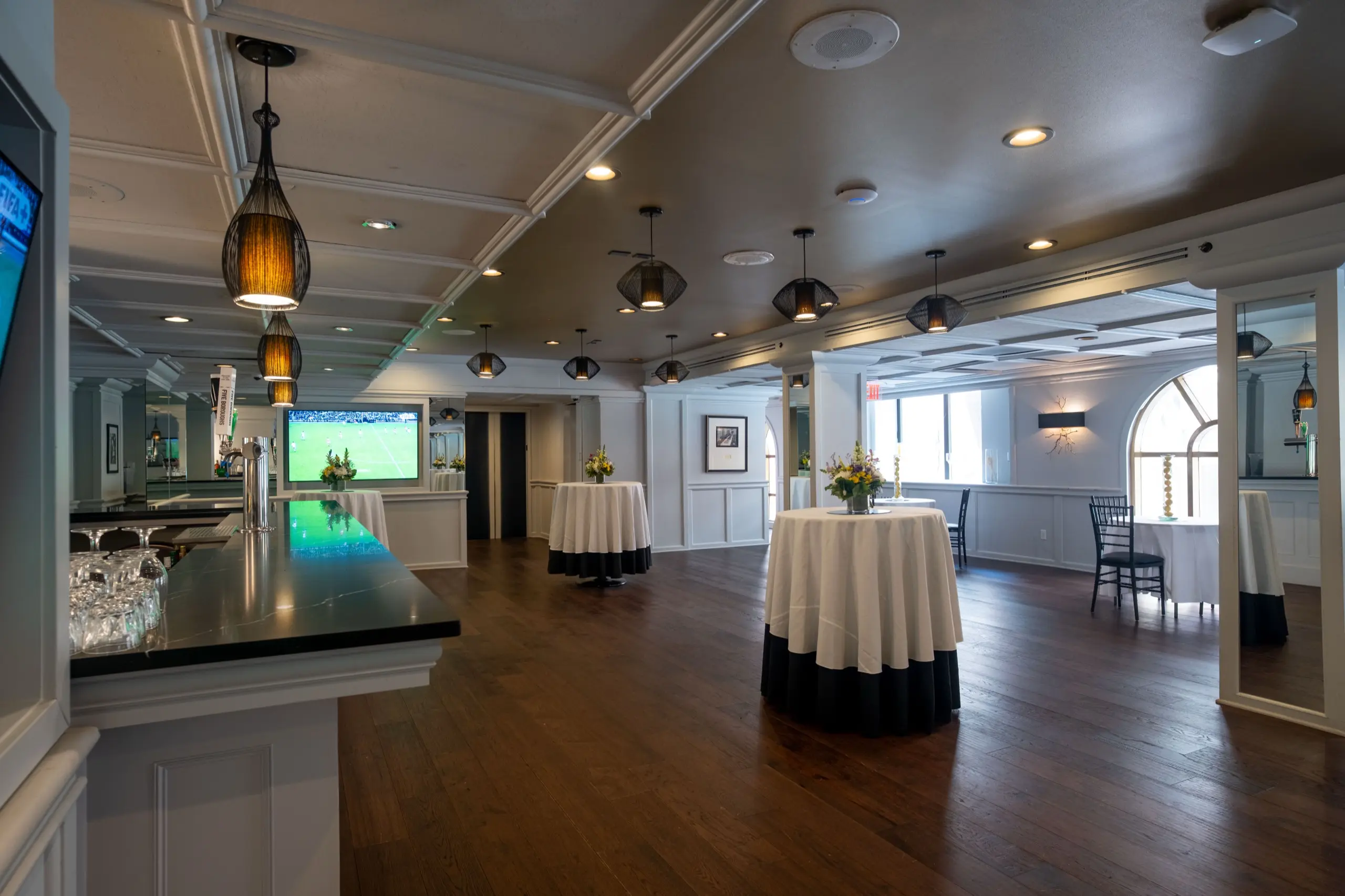 Manhattan Manor's bar and cocktail tables, an arched window beyond