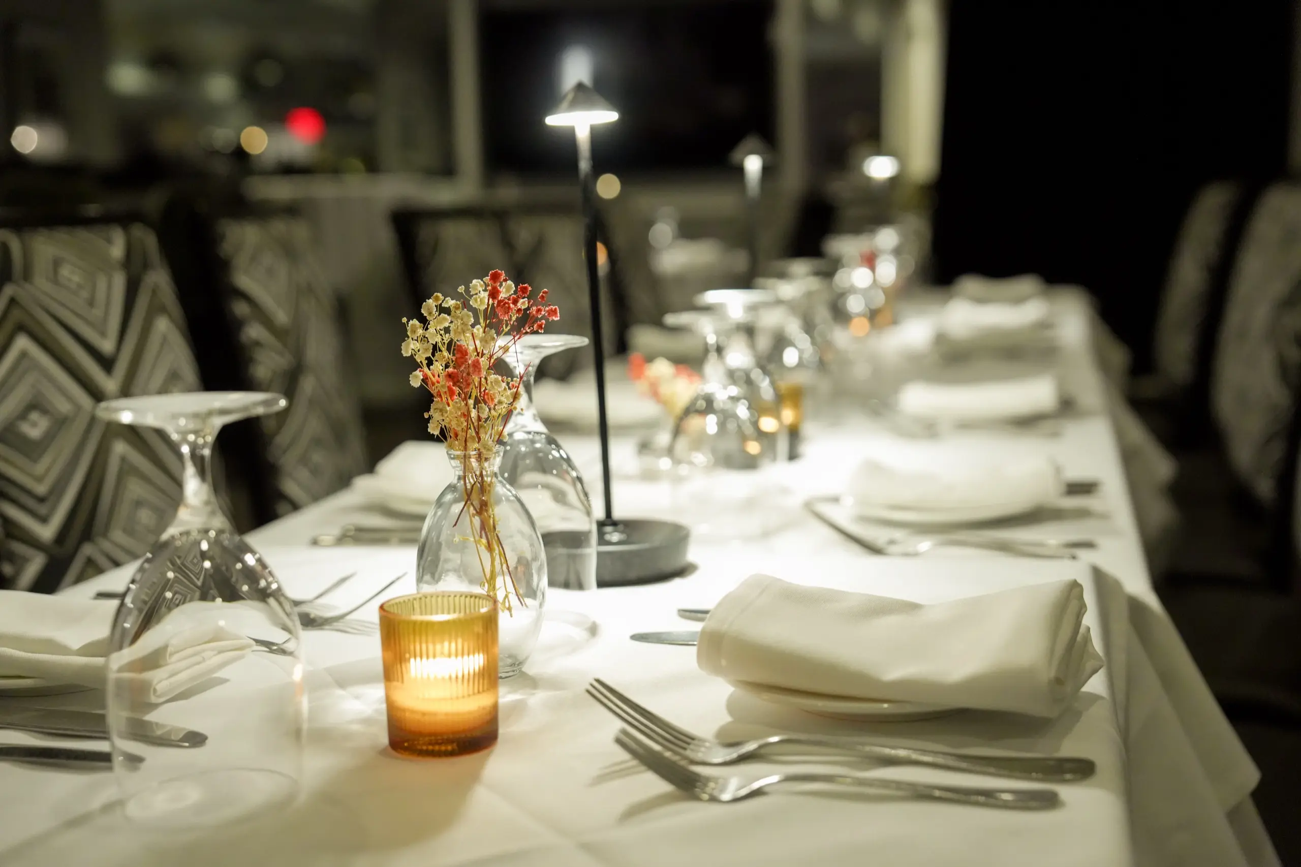 A dinner table set with candles and dried flowers in the dining room
